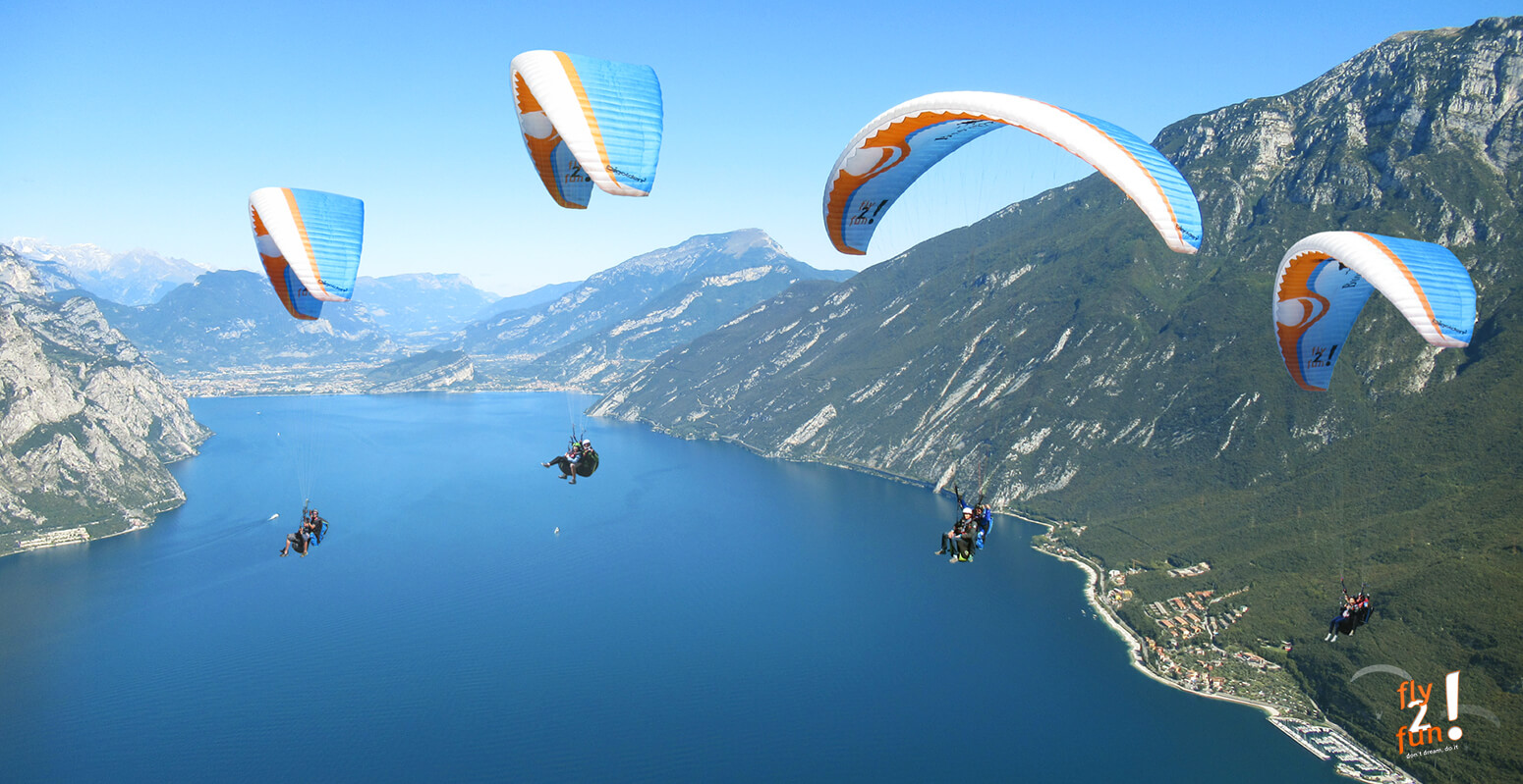 in-questa-immagine-vediamo-un-gruppo-in-parapendio-biposto-pilotati-da-piloti-professionisti-in-volo-sul-lago-di-Garda